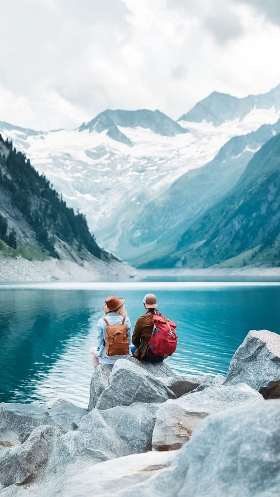 Deux randonneurs au bord d'un lac turquoise réfléchissent à leur mutuelle santé et prévoyance.