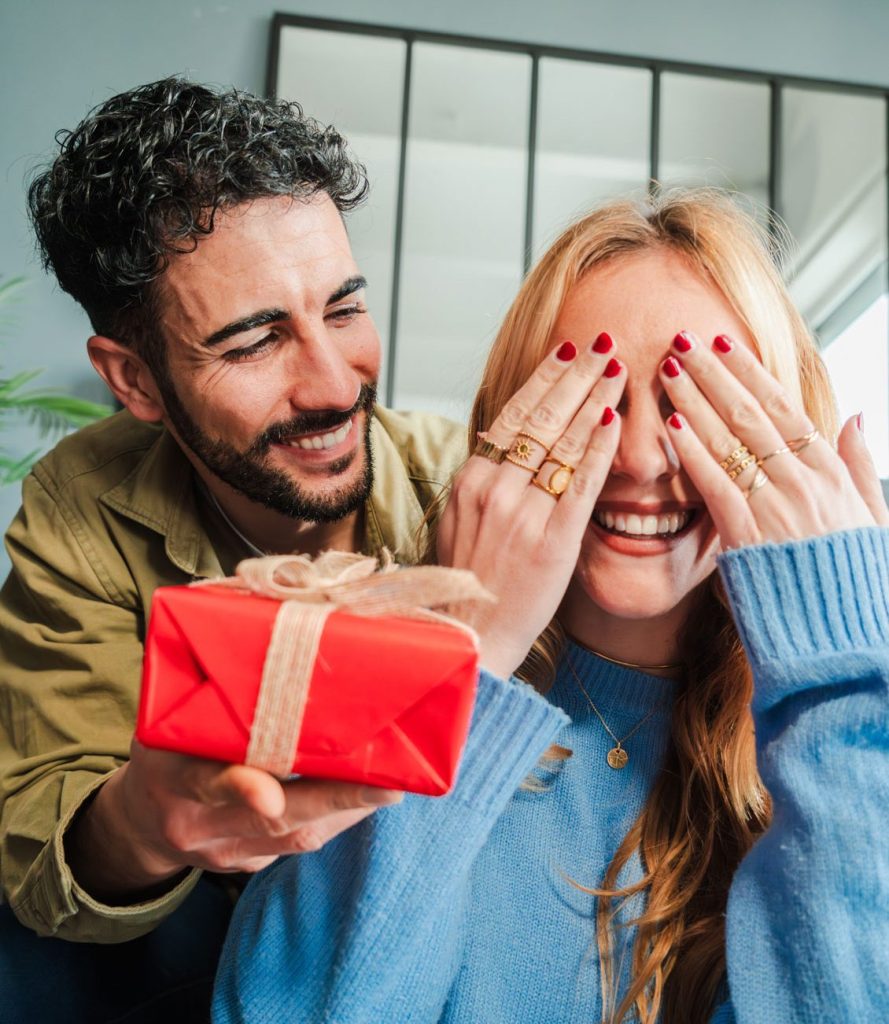Un homme offre un cadeau à une femme pour leur nouvelle mutuelle santé, protection sociale assurée.