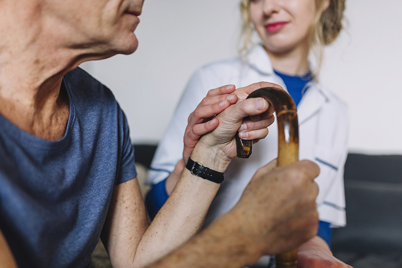 Un patient tenant une canne discute mutuelle santé avec un professionnel de santé bienveillant.