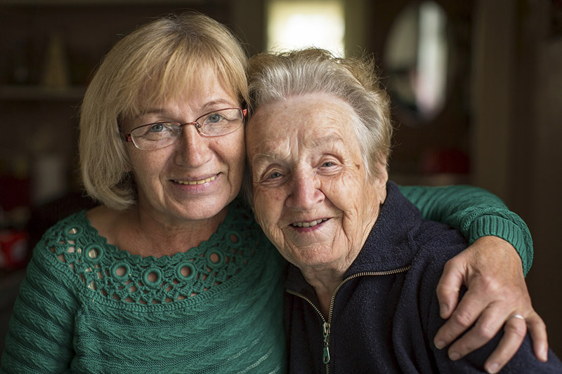 Deux femmes souriantes, générations différentes, discutent ensemble d'assurance santé et de protection sociale.