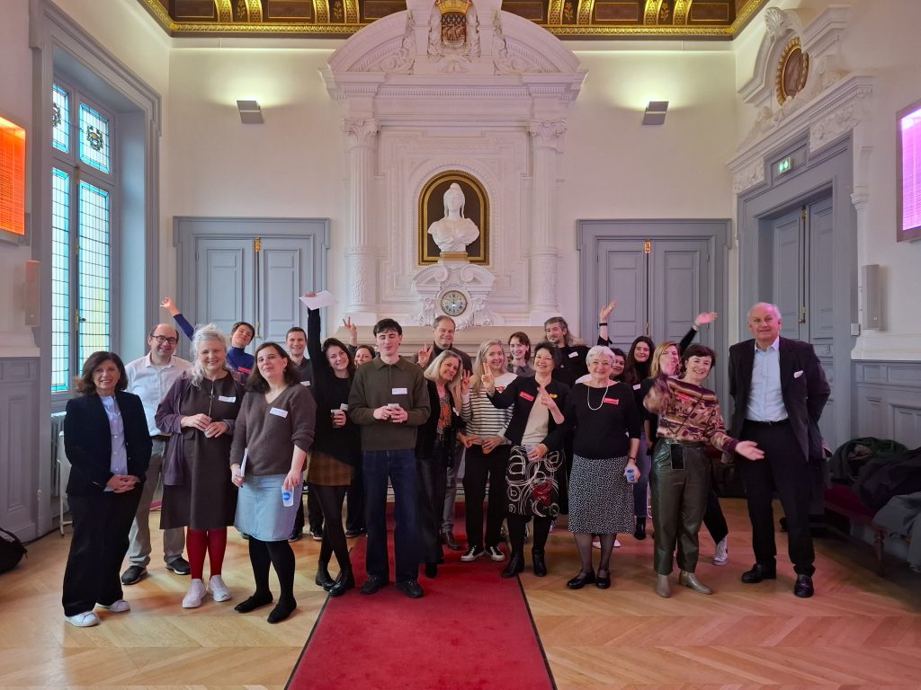Groupe souriant lors d'un événement mutuelle santé dans une salle ornée, protection sociale.