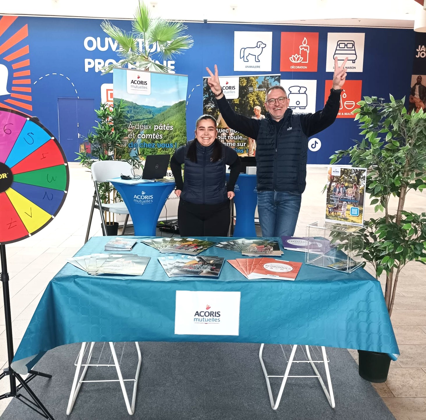 Stand Acoris Mutuelles avec deux personnes, des brochures et des supports de communication dans un centre commercial.
