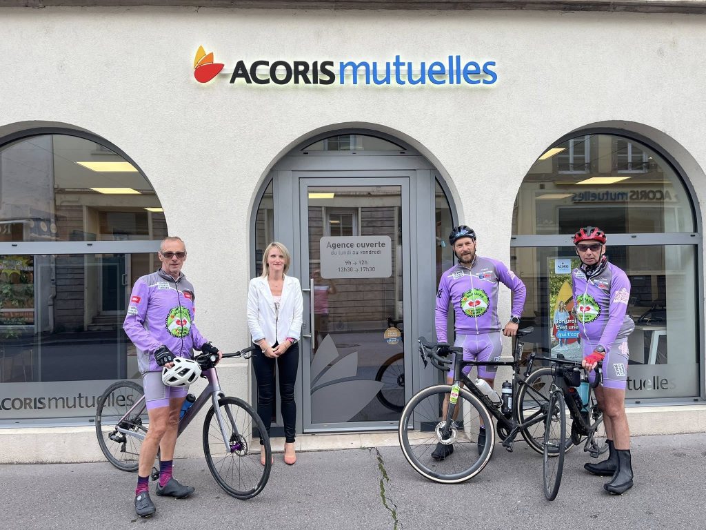 Quatre personnes devant une agence Acoris Mutuelles, dont trois en tenue de cyclisme avec leurs vélos devant l’entrée.