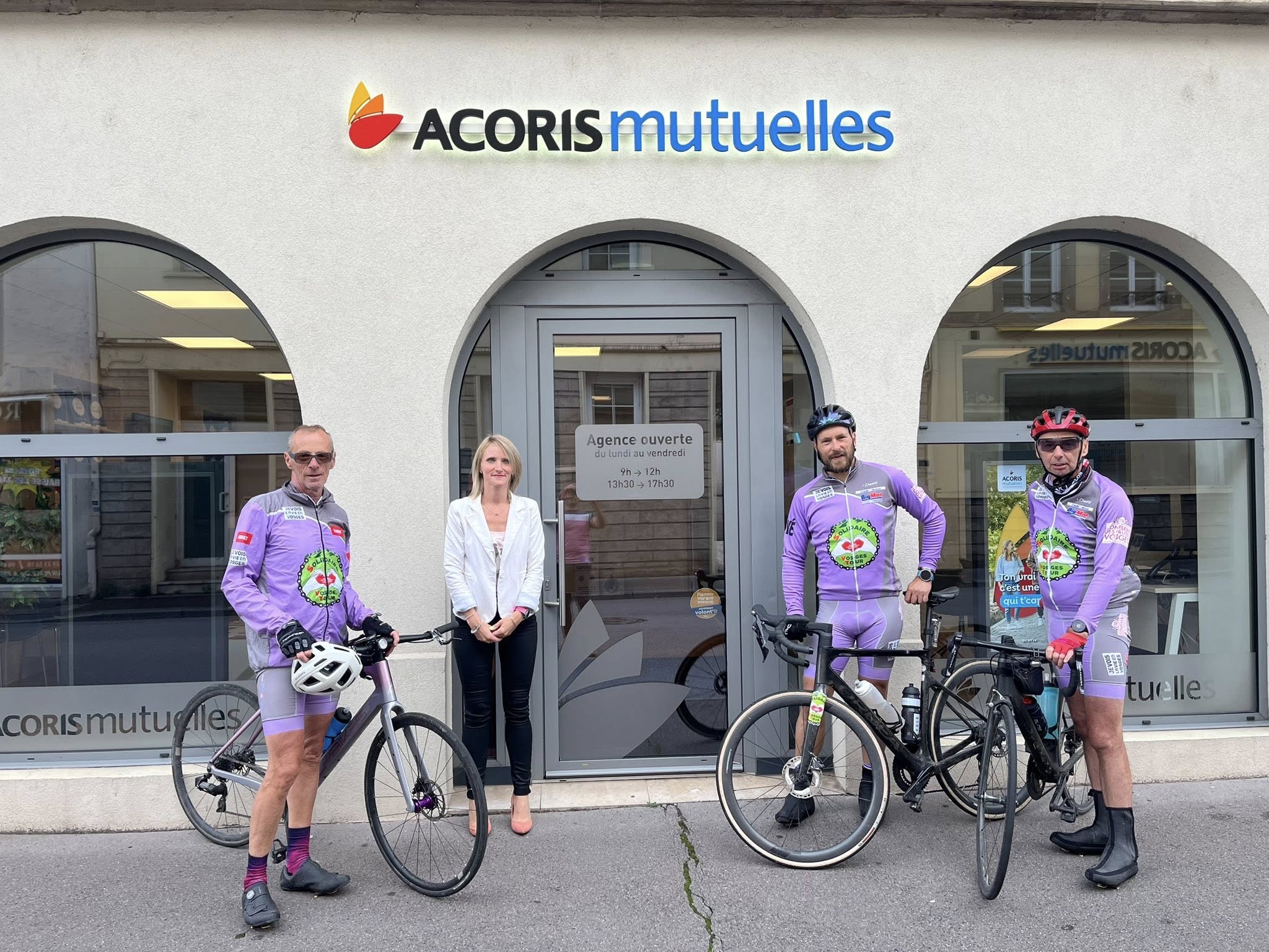Quatre personnes devant une agence Acoris Mutuelles, dont trois en tenue de cyclisme avec leurs vélos devant l’entrée.