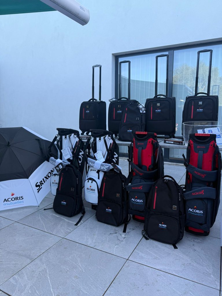 Lots de sacs et valises de golf «ACORIS Mutuelles » exposés en extérieur lors d’un événement.