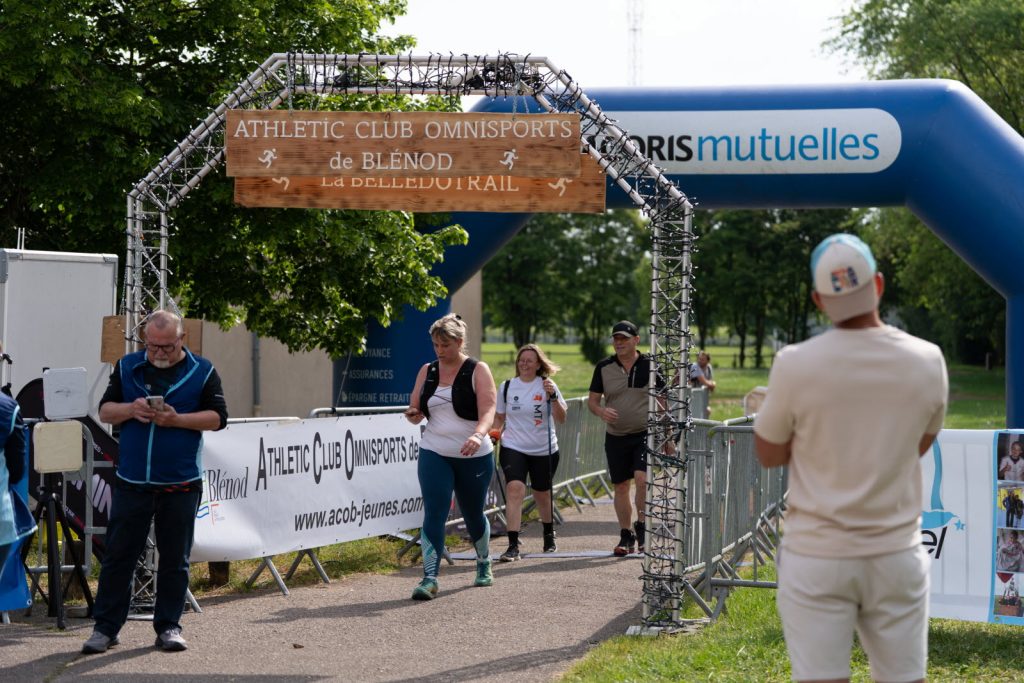 Participants franchissant l’arche d’arrivée de la Bellédotrail à Blénod, avec signalétique ACORIS Mutuelles en arrière-plan.