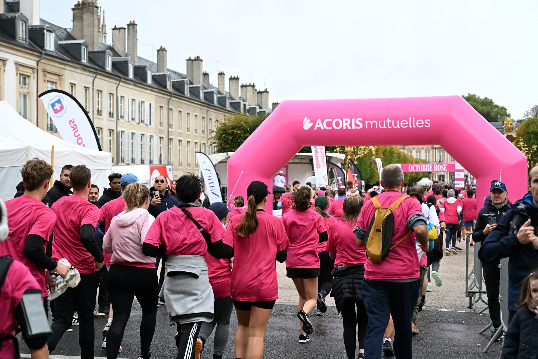 Course Octobre Rose à Nancy avec les participants passant sous une arche ACORIS Mutuelles pour sensibiliser au dépistage du cancer du sein.