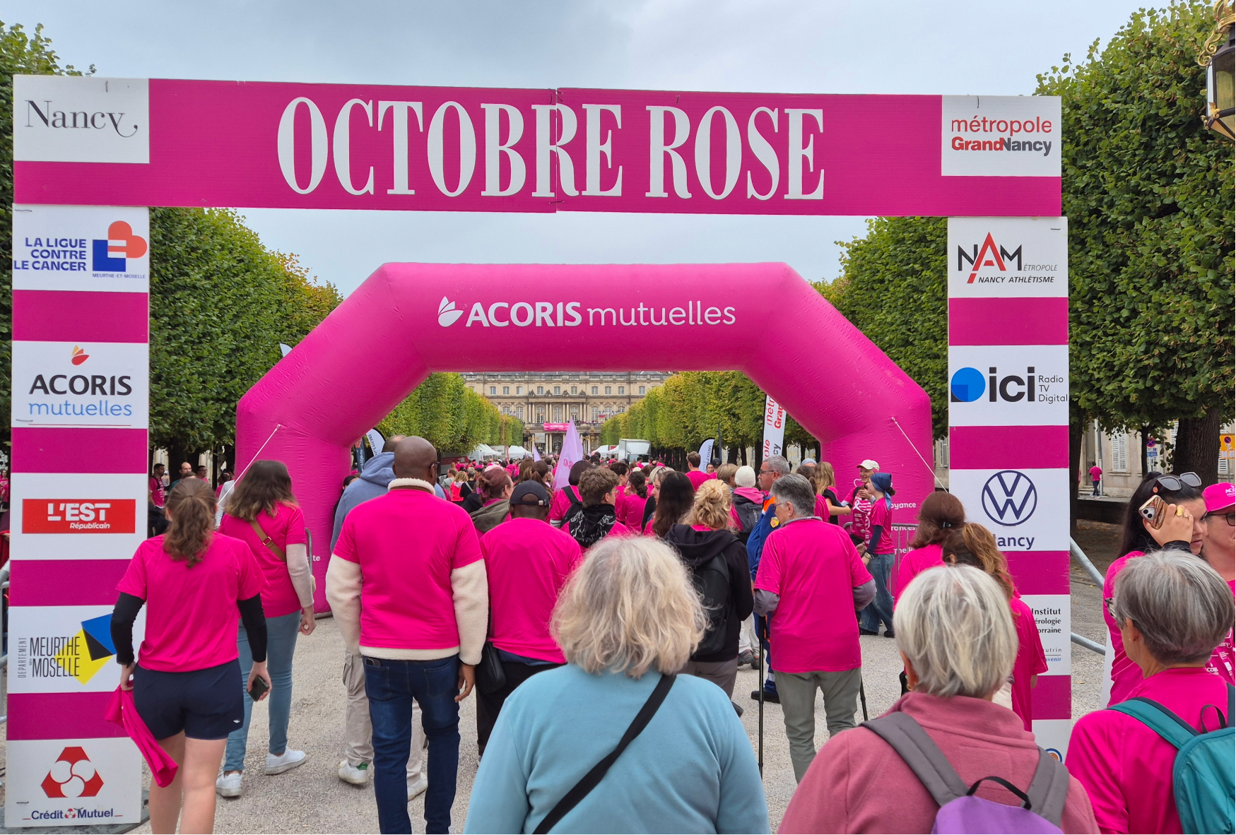 Participants à la marche Octobre Rose à Nancy passant sous l’arche ACORIS Mutuelles lors d’un événement de sensibilisation au dépistage du cancer du sein.