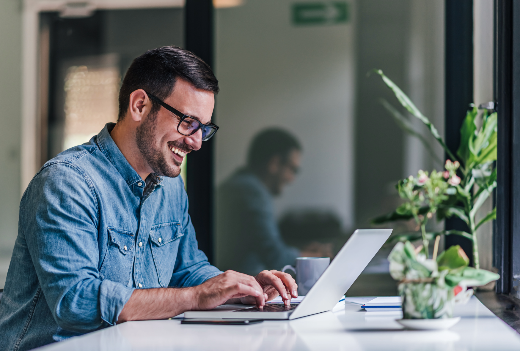 Personne travaillant sur un ordinateur portable dans un espace de bureau lumineux.