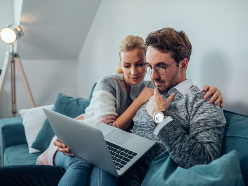 Couple consultant les garanties d'une complémentaire santé en ligne sur un ordinateur portable depuis son domicile.