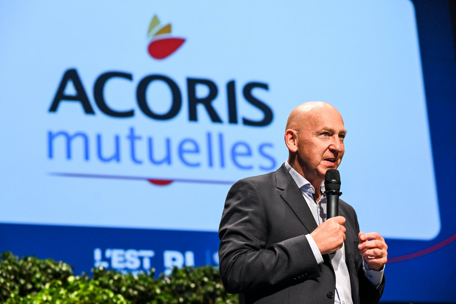 Prise de parole sur scène lors d’un événement institutionnel, devant un écran affichant le logo ACORIS Mutuelles.